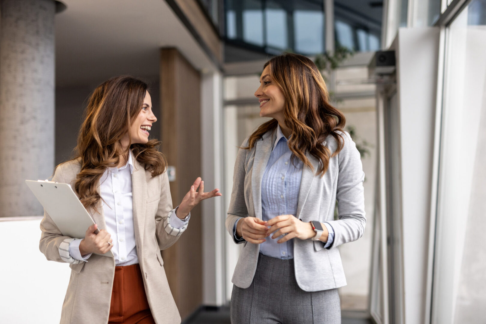 Two businesswomen chatting while walking in office